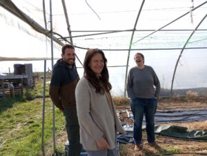 Trois personnes sourient au photographe dans une serre