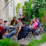 Des personnes attablées en extérieur écoutent une personne debout lors d'une formation