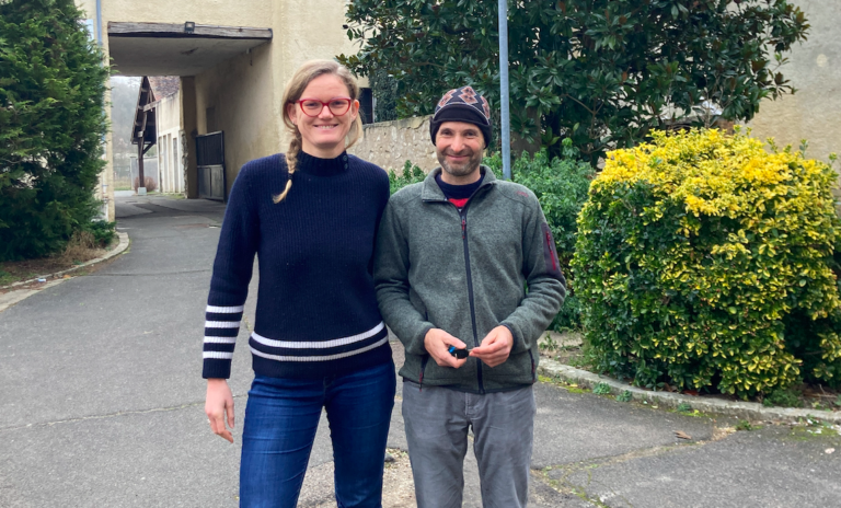 Photo des deux cogérants Agnès et Saturnin lors du séminaire de la coopérative Les Champs des possibles. Ils posent en extérieur dans une cour devant un buis.
