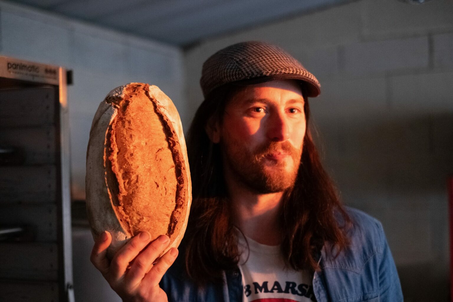 Un homme pose avec un pain dans la main