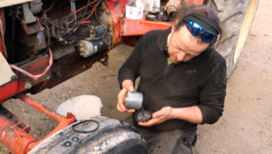 Un homme étudie une pièce du moteur de son tracteur